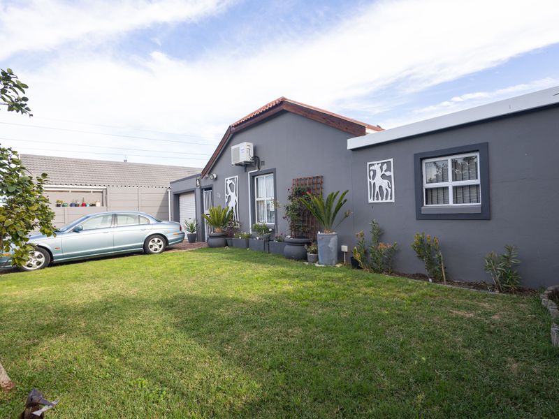 Front view of a residential house featuring a grey facade, tiled roof, and a well-maintained front lawn.