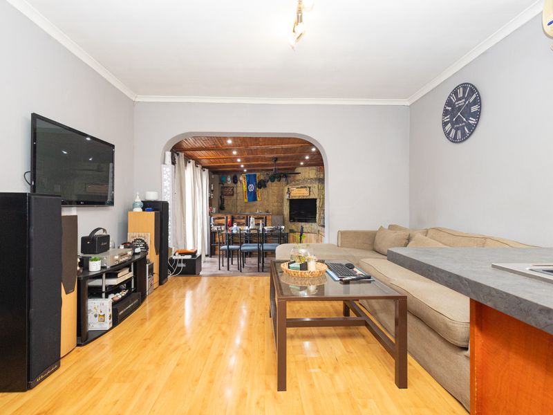 Open plan living area featuring laminate flooring, a stone feature wall in the adjoining space, and an archway transition between rooms.