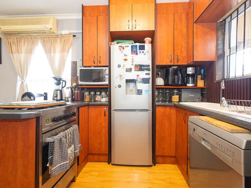 A functional kitchen featuring wood-toned cabinetry, laminate countertops, a built-in oven, and a double sink, providing a practical workspace with integrated storage.