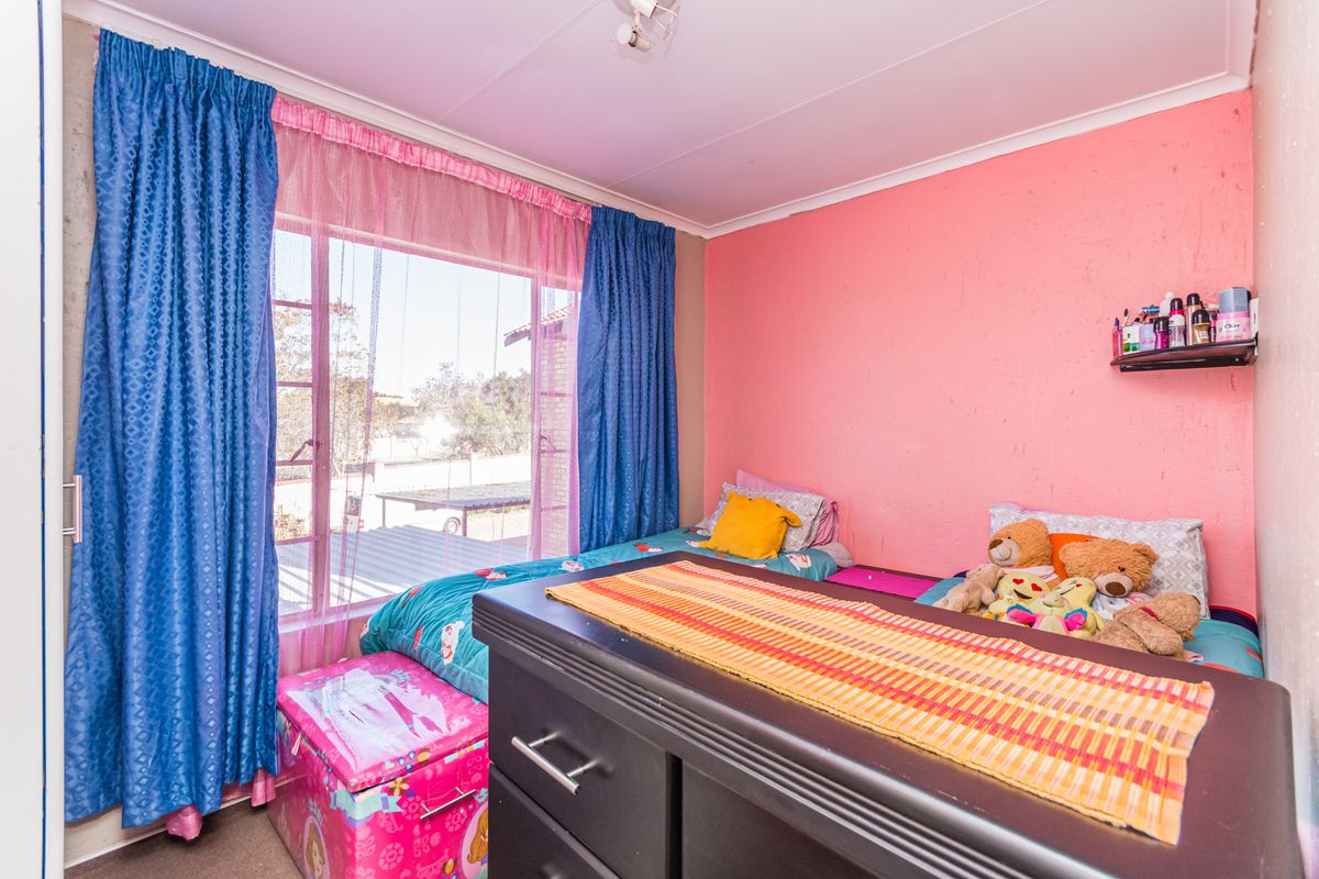 A bedroom featuring a large window with natural light and pink painted walls, providing a functional space for rest.