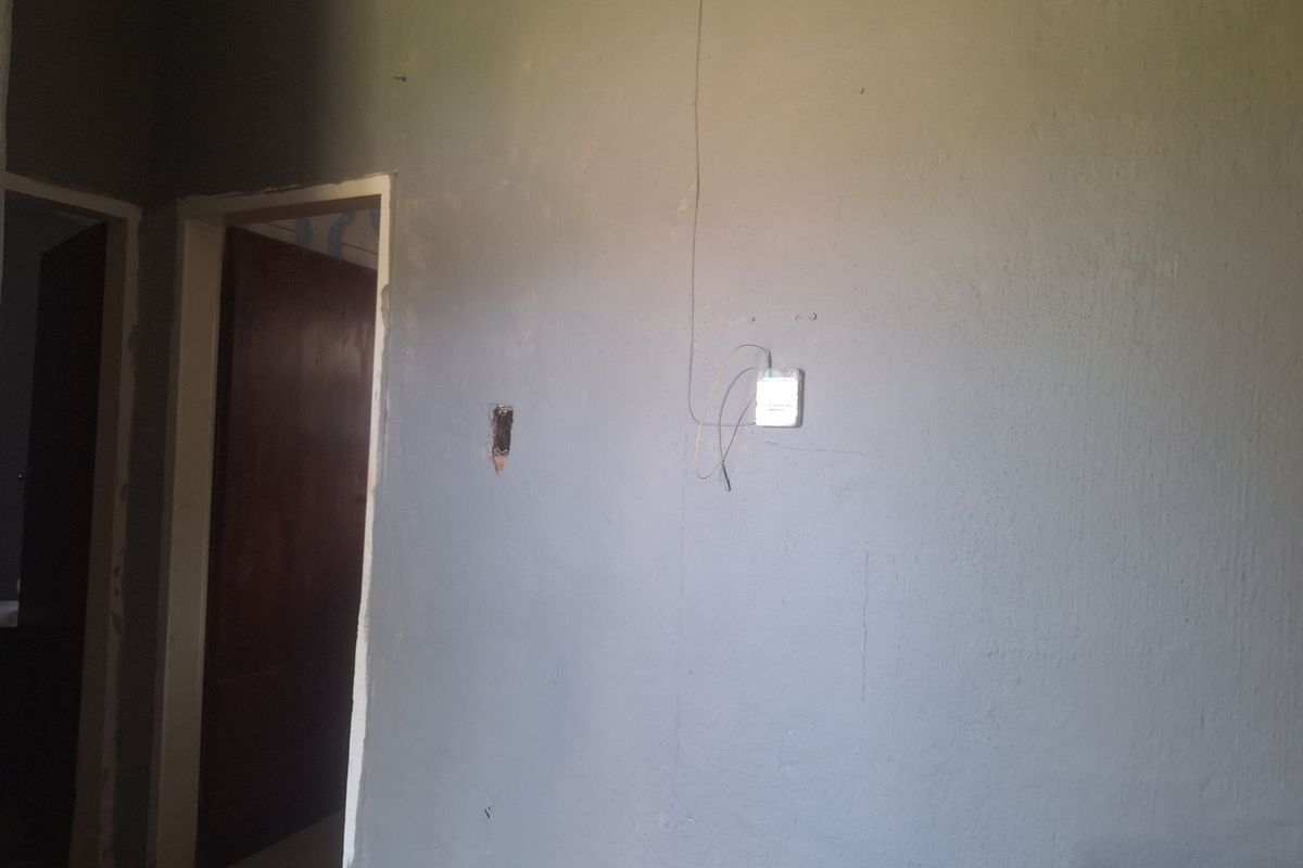 An interior hallway space featuring unfinished wall surfaces and exposed electrical wiring, requiring cosmetic repairs and finishing.