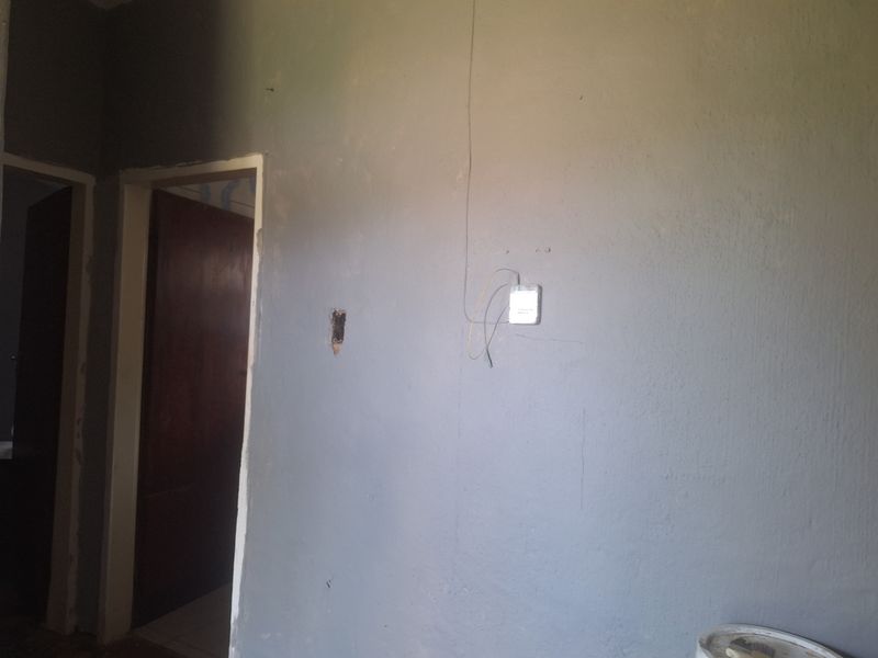 An interior hallway space featuring unfinished wall surfaces and exposed electrical wiring, requiring cosmetic repairs and finishing.