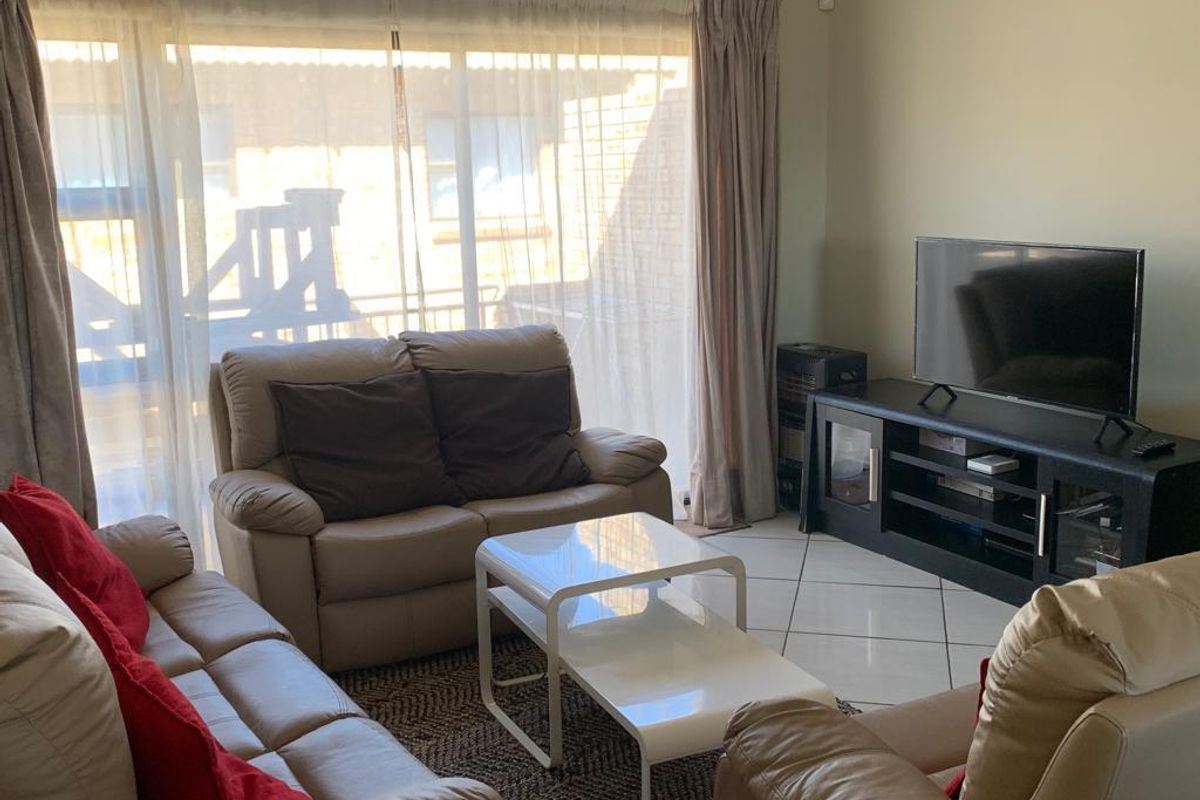 A comfortable living room featuring tiled flooring and a large sliding glass door that provides natural light and access to the outdoor area.