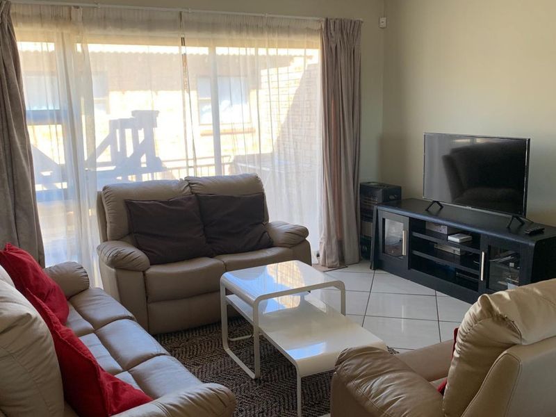 A comfortable living room featuring tiled flooring and a large sliding glass door that provides natural light and access to the outdoor area.