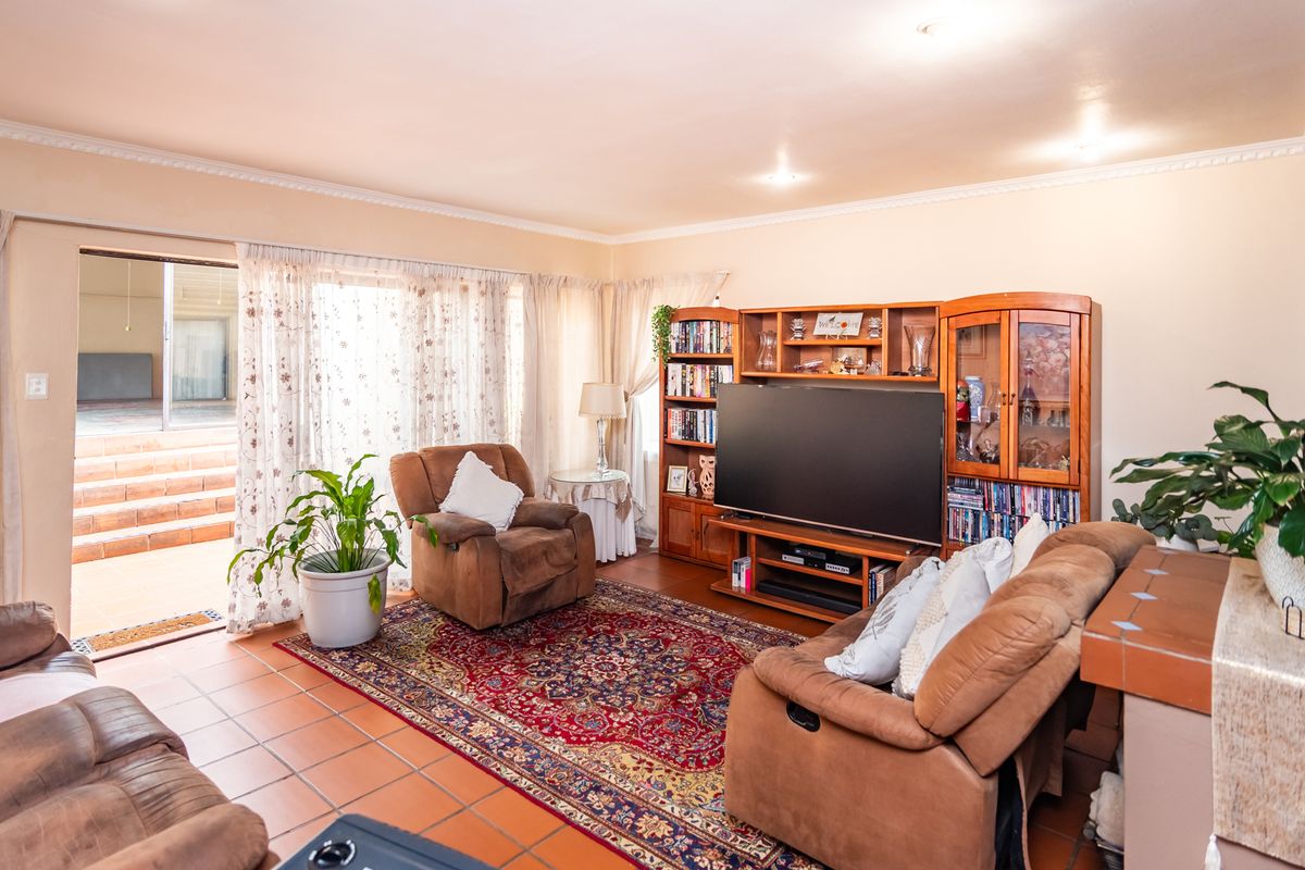 A comfortable living room featuring tiled flooring, coved ceilings, and a sliding glass door providing direct access to the outdoor patio area.