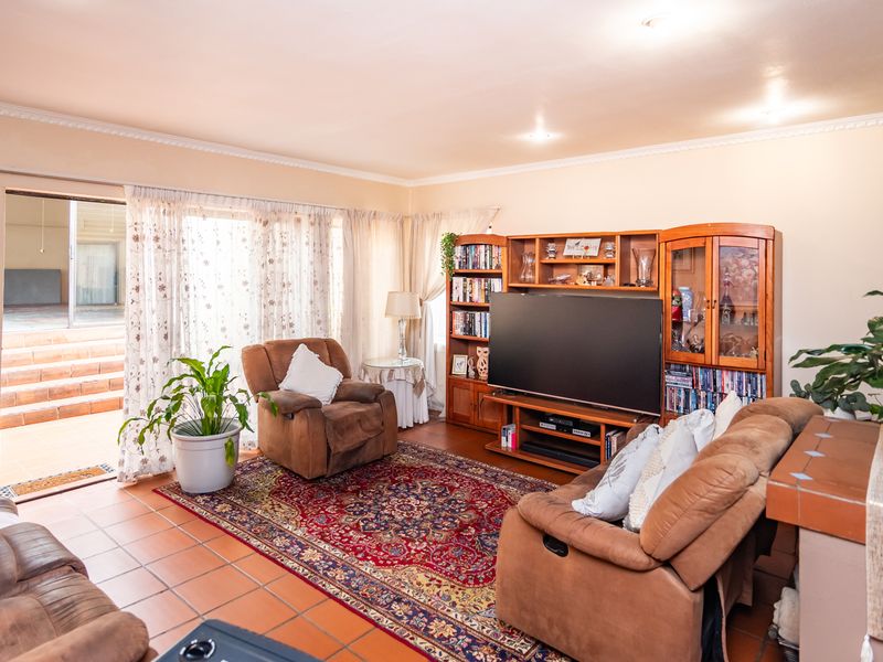 A comfortable living room featuring tiled flooring, coved ceilings, and a sliding glass door providing direct access to the outdoor patio area.