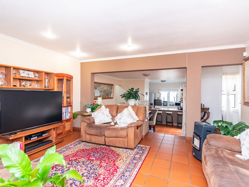 Open plan living area featuring terracotta floor tiles, recessed lighting, and a seamless flow into the adjacent kitchen with a breakfast counter.