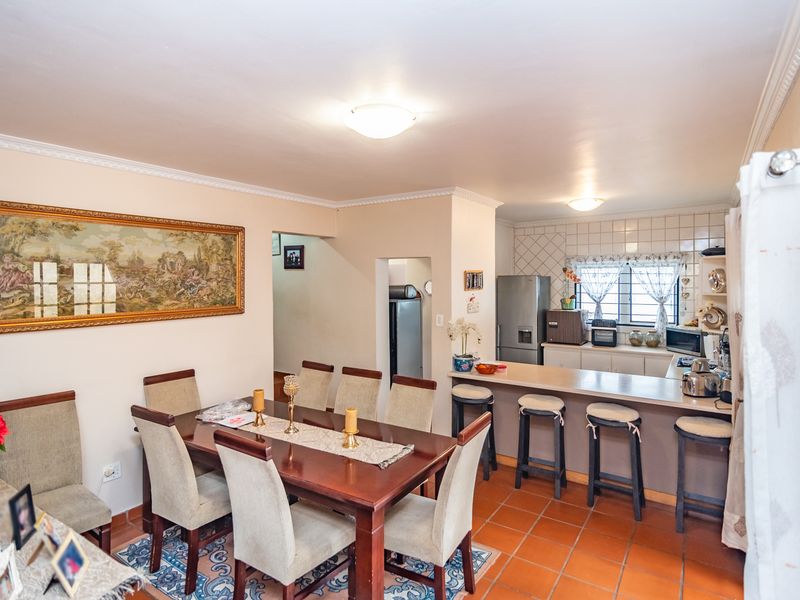 Open plan dining and kitchen area featuring a breakfast bar, tiled flooring, and classic crown molding, creating a functional and connected living space.