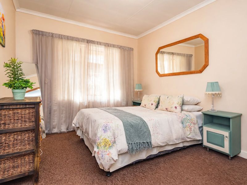 A cozy bedroom featuring carpeted flooring, neutral wall finishes, and large windows with curtain rails, providing a comfortable and functional sleeping space.