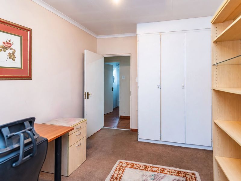A functional bedroom featuring built-in cupboards, carpeted flooring, and direct access to an adjoining room.