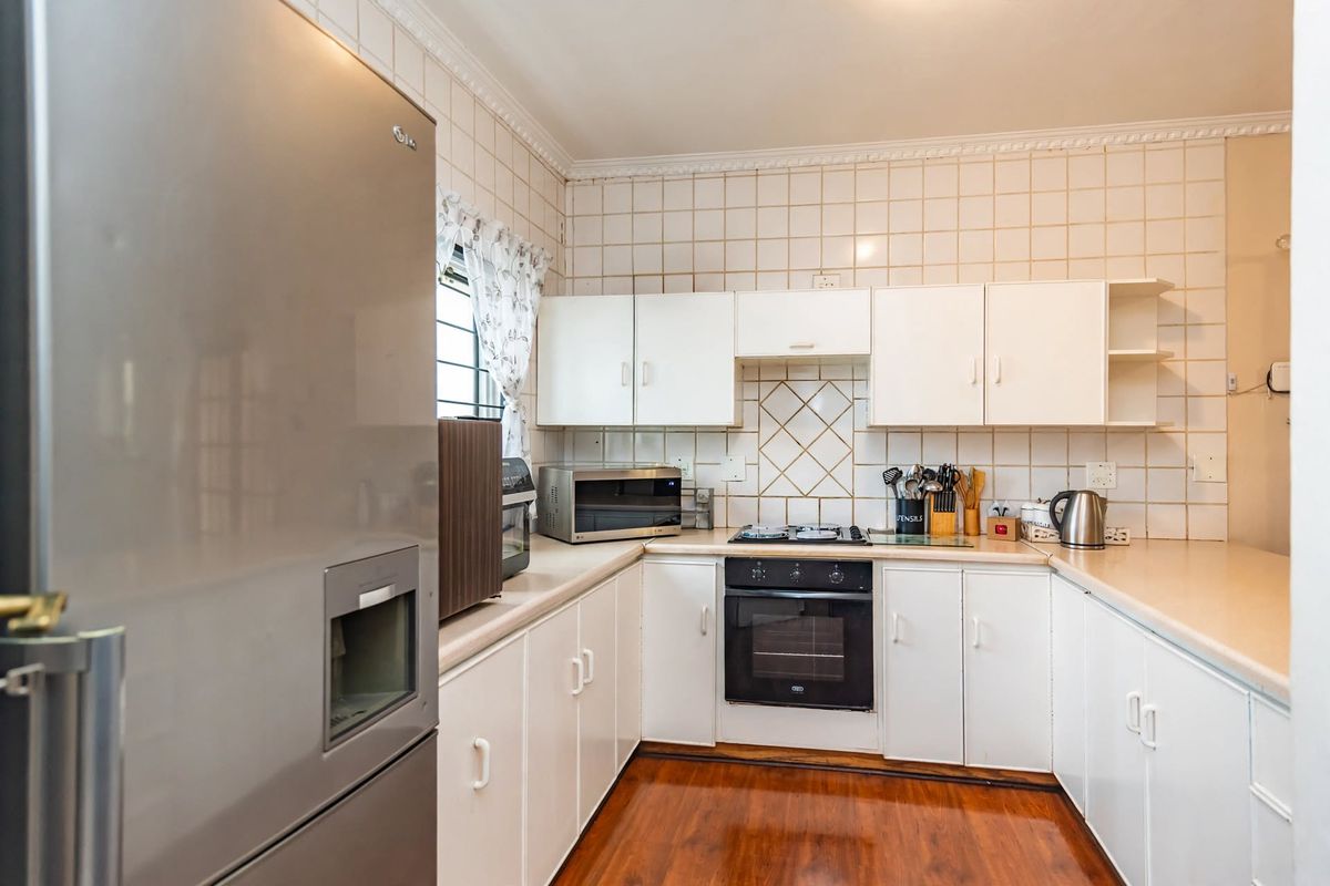 A functional kitchen featuring white cabinetry, laminate countertops, a built-in oven with gas hob, and tiled backsplash, offering a classic layout.