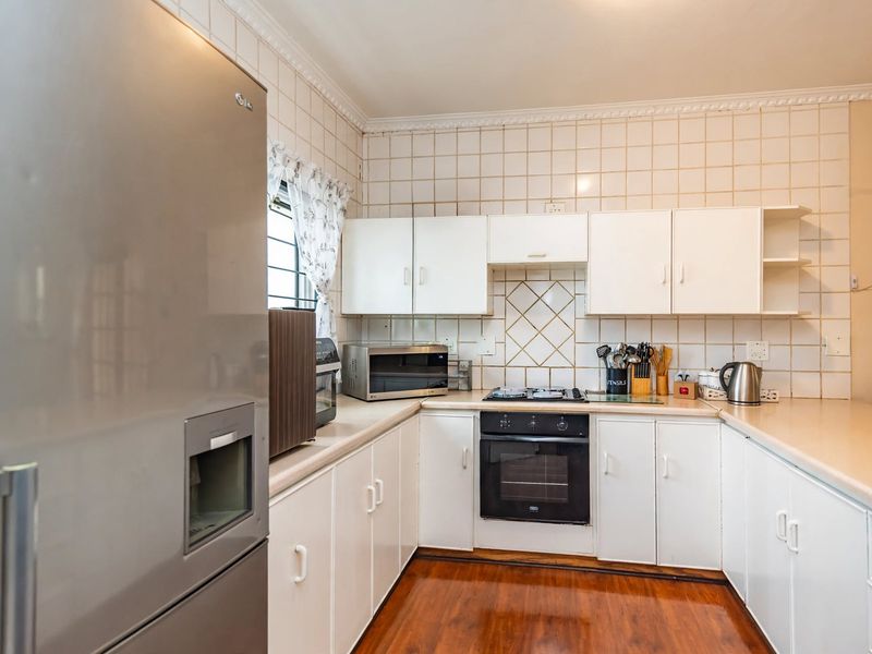 A functional kitchen featuring white cabinetry, laminate countertops, a built-in oven with gas hob, and tiled backsplash, offering a classic layout.
