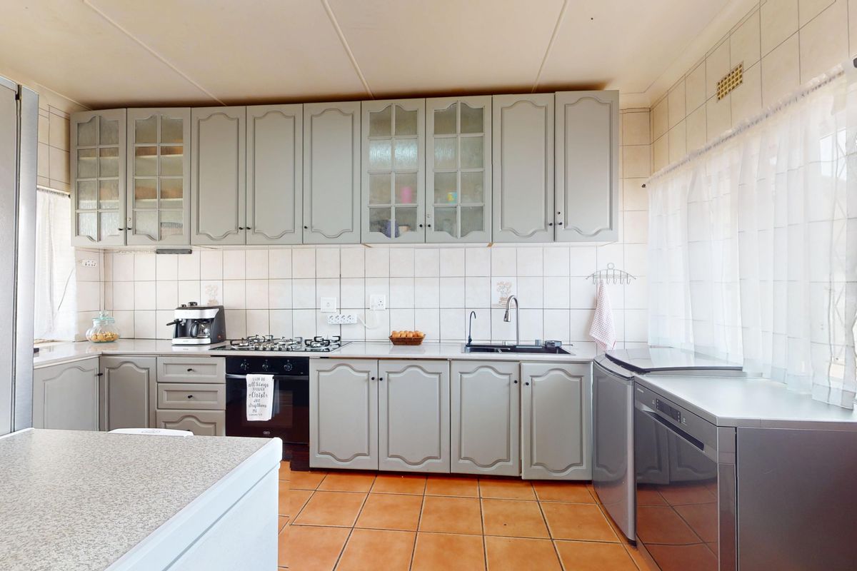 Functional kitchen featuring grey built-in cabinetry, gas hob, built-in oven, tiled backsplash, and ceramic floor tiles.