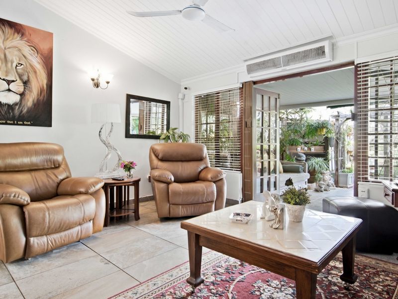 A comfortable living room featuring tiled floors, a ceiling fan, and split-system air conditioning, with direct access to an outdoor patio area through french doors.