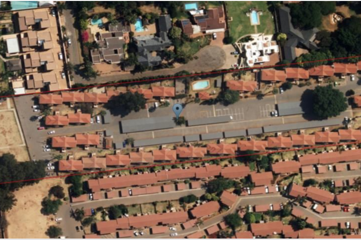 Aerial view of the apartment complex showing the layout of residential units, communal parking facilities, and surrounding grounds.