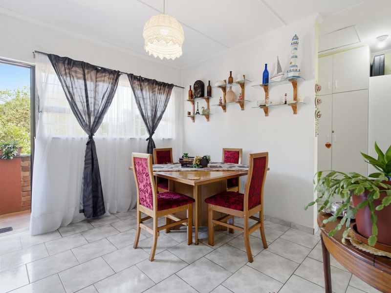 A dining area featuring tiled flooring, built-in storage cupboards, and a sliding door providing access to an outdoor balcony space.