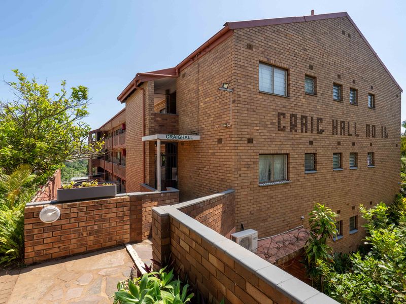 Exterior view of Craighall apartment building featuring face brick construction, paved walkways, and established garden surroundings.