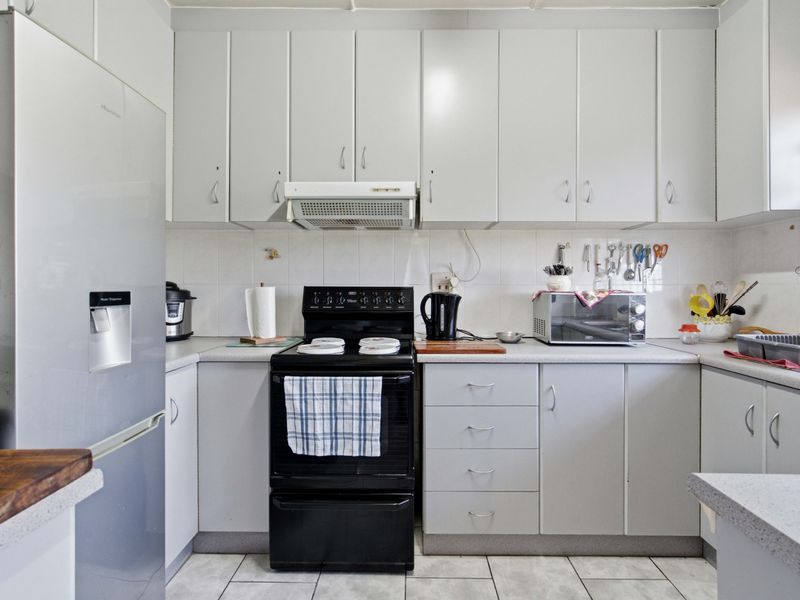 A functional kitchen featuring light-toned cabinetry, laminate countertops, a tiled backsplash, and tiled flooring, providing a practical workspace.