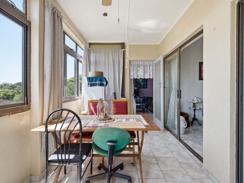 Enclosed balcony or sunroom featuring tiled flooring, large windows, and sliding glass doors providing access to the interior living space.