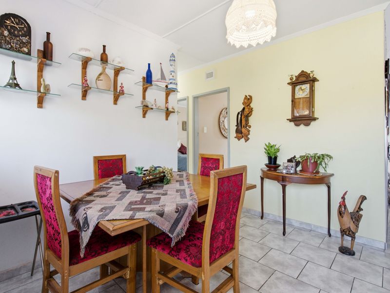 A dining area featuring neutral tiled flooring and wall-mounted glass shelving, providing a functional space for meals.