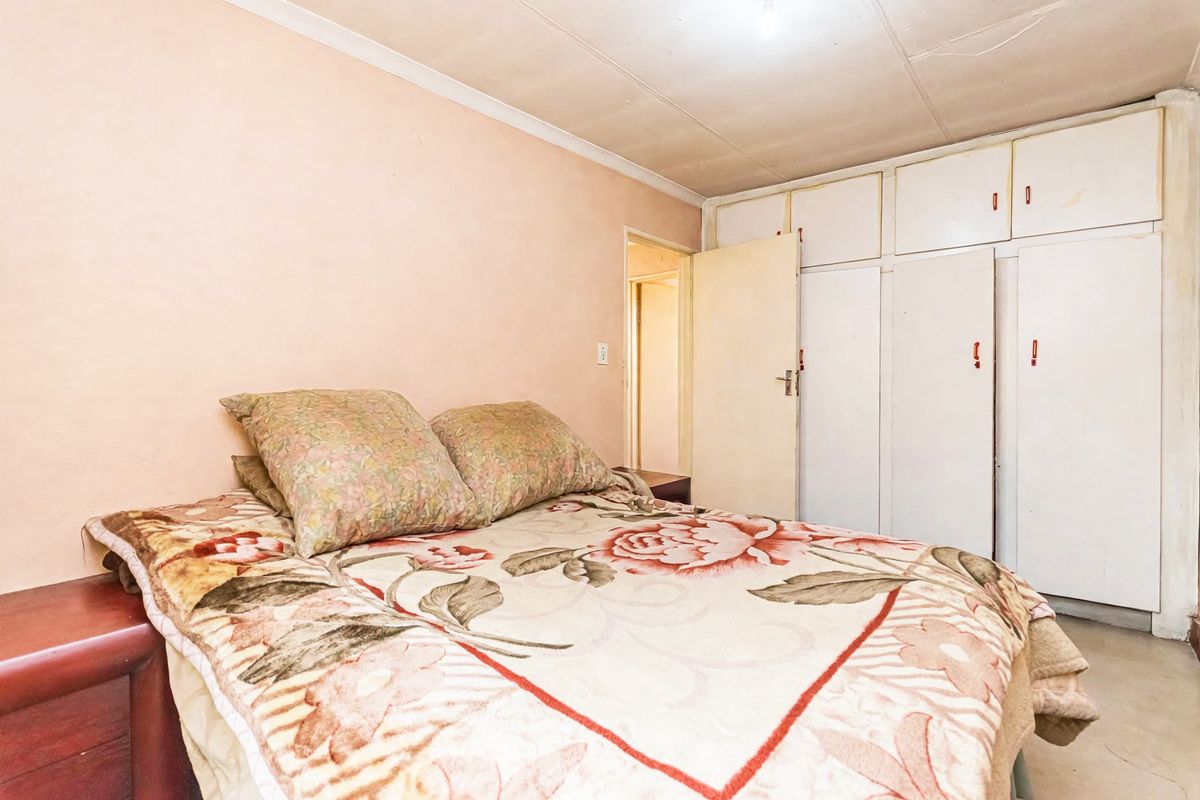 A bedroom featuring built-in cupboards with overhead storage and standard ceiling finishes, requiring cosmetic updates to improve the overall aesthetic.