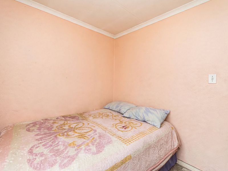 A compact bedroom featuring plain walls with coving and a standard electrical outlet.