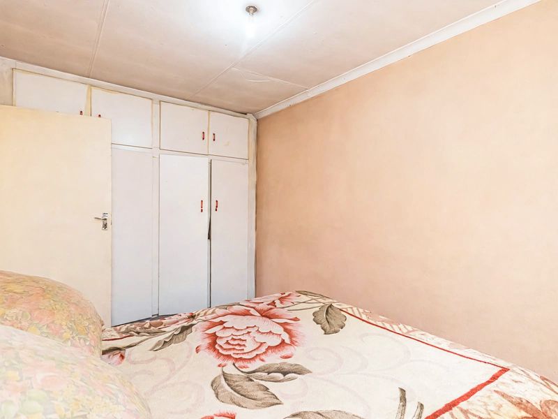 A bedroom featuring built-in cupboards with overhead storage. The room requires cosmetic updates to the ceiling and wall finishes.