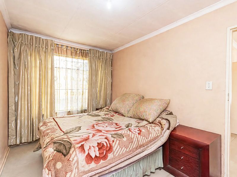 A bedroom featuring security bars on the window and cove cornicing, requiring cosmetic updates to the ceiling and wall finishes.