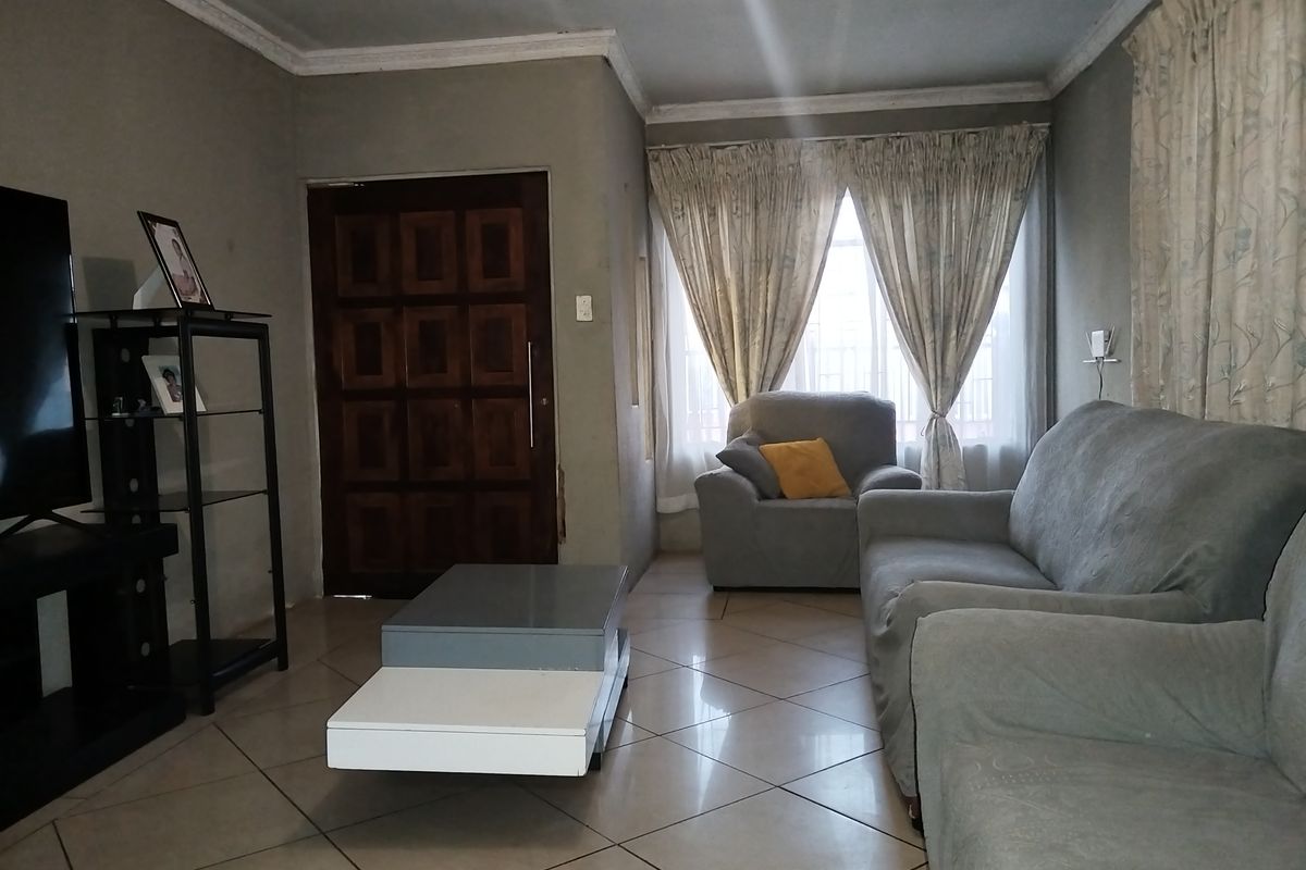 A living room featuring tiled flooring, crown molding, and a solid wood entrance door, providing a functional and comfortable living space.