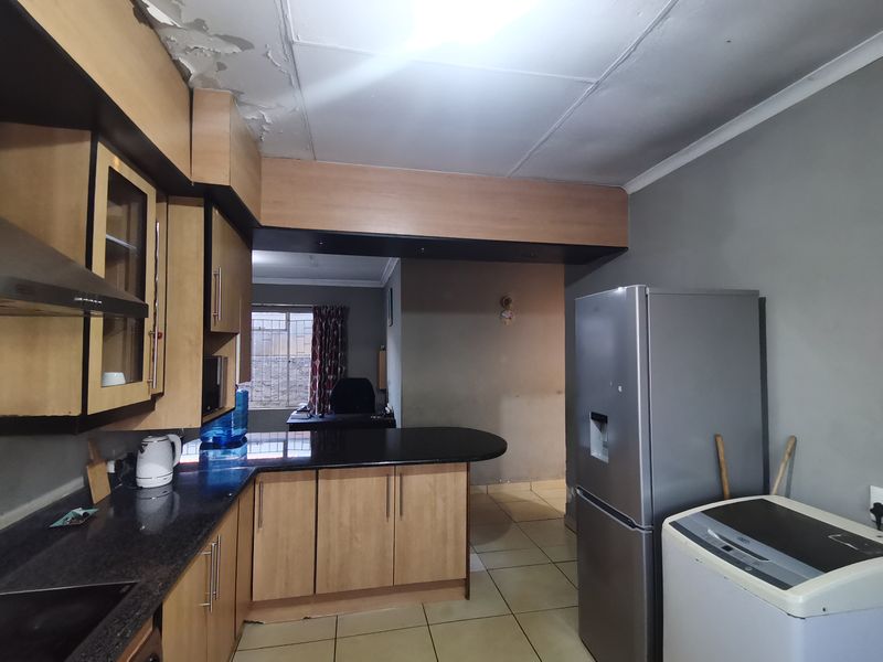 Kitchen featuring built-in wooden cabinetry, granite countertops, and an extractor fan. The ceiling shows signs of water damage and peeling paint.