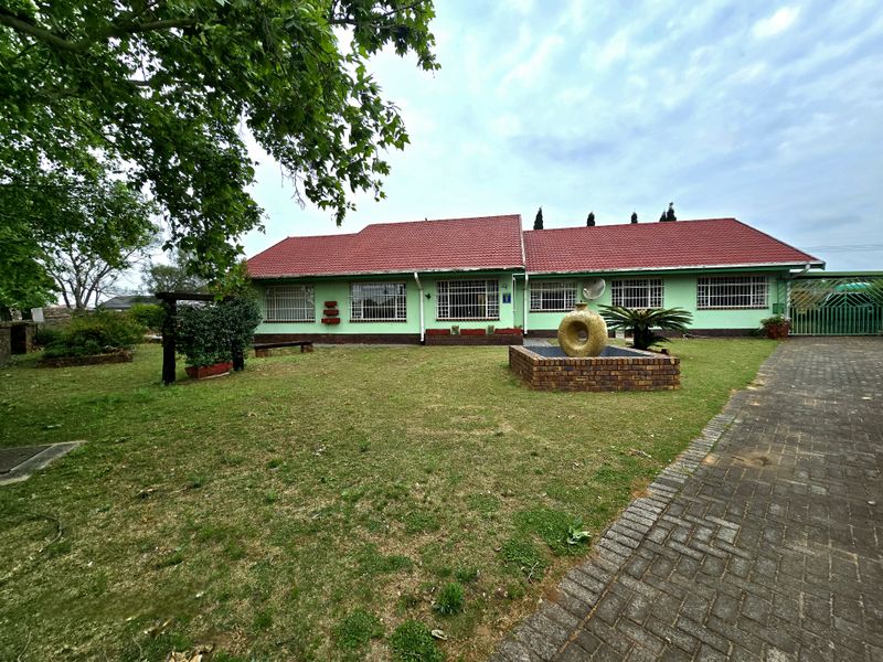 Front view of a single-story house featuring a red tiled roof, security bars on windows, and a paved driveway leading to a garden area.