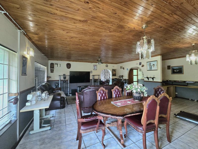 Spacious open-plan living and dining area featuring a distinctive timber tongue and groove ceiling, ceramic tiled flooring, and classic archway architectural details.