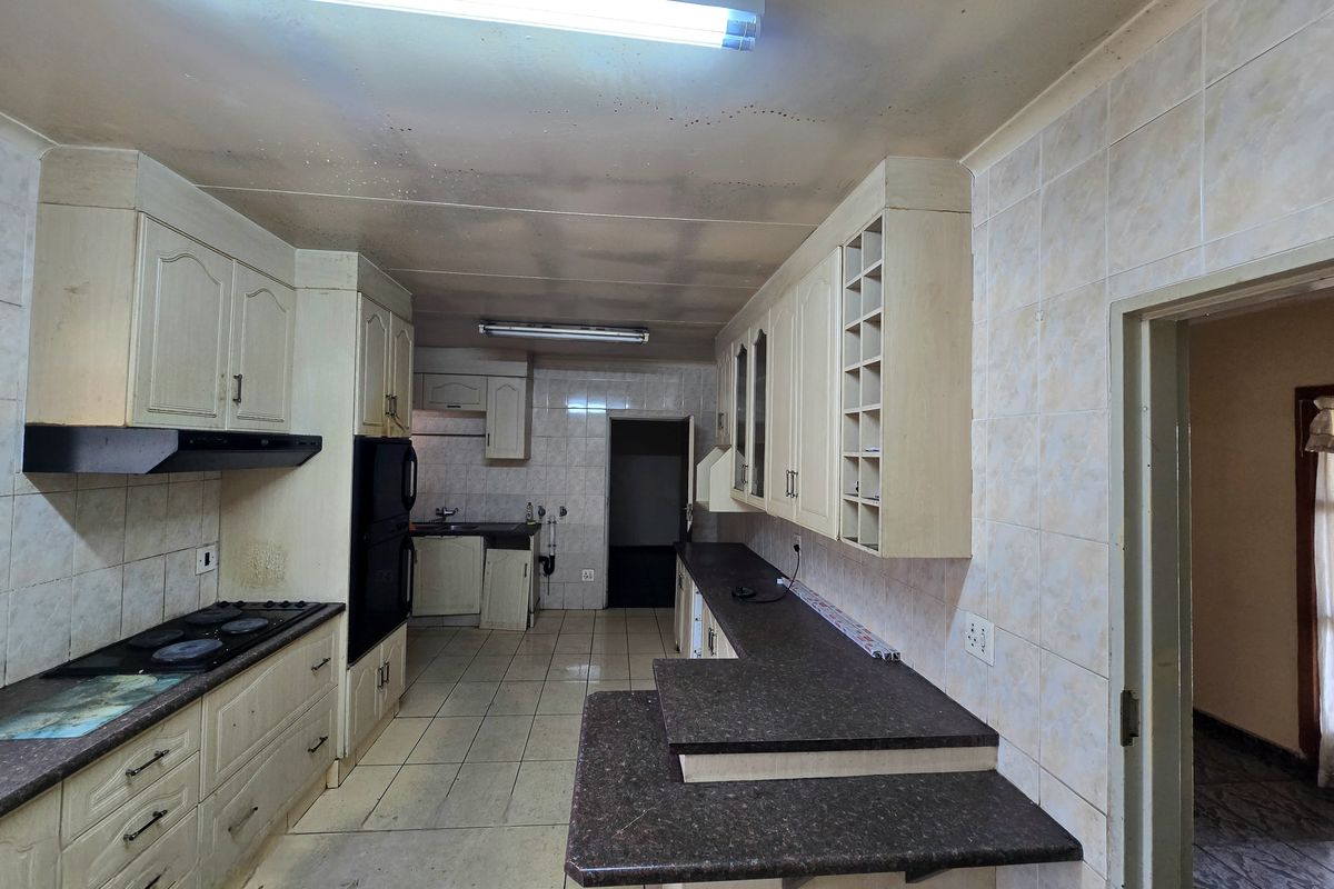 A dated kitchen featuring built-in cabinetry, laminate countertops, and tiled finishes, offering a functional layout ready for modernization and renovation.