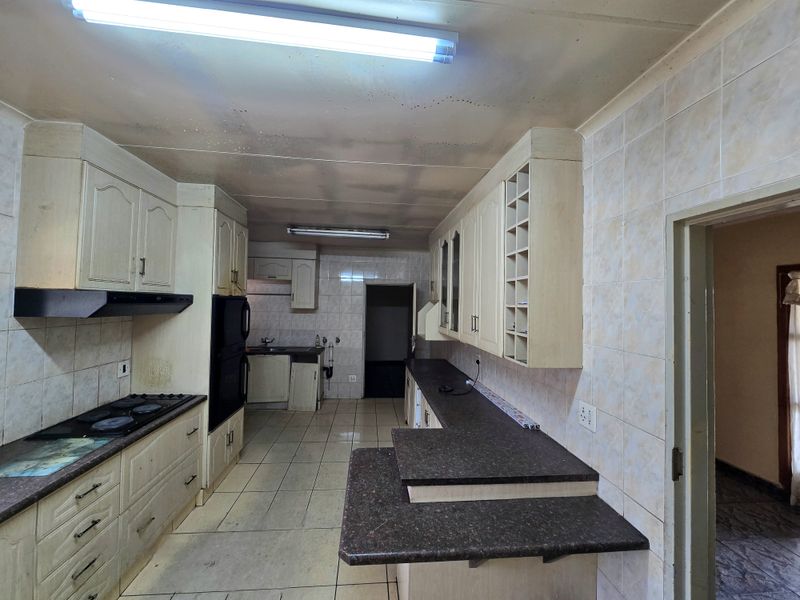 A dated kitchen featuring built-in cabinetry, laminate countertops, and tiled finishes, offering a functional layout ready for modernization and renovation.