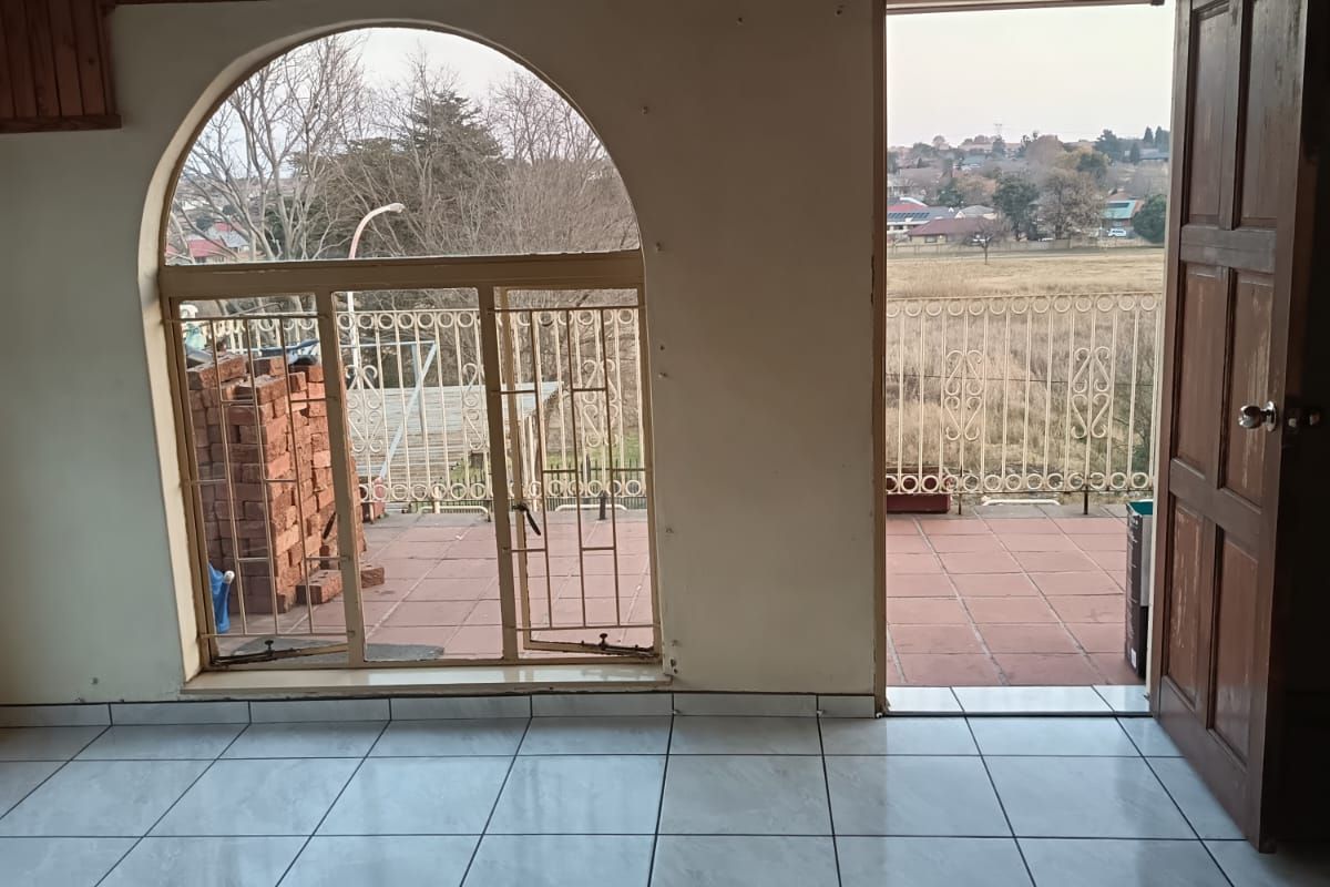 Empty living area featuring tiled floors, a timber-clad ceiling, and an arched window with direct access to an outdoor balcony.