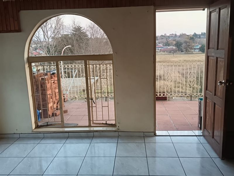 Empty living area featuring tiled floors, a timber-clad ceiling, and an arched window with direct access to an outdoor balcony.