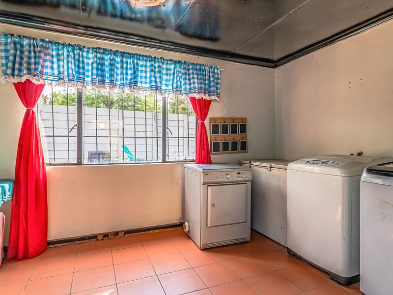 A functional laundry room featuring tiled flooring and a window with security bars, providing a practical space for household utility tasks.