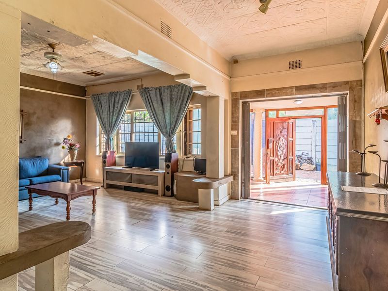 Spacious living area featuring wood-look tile flooring, decorative textured ceilings, and direct access to the exterior through a carved wooden door.