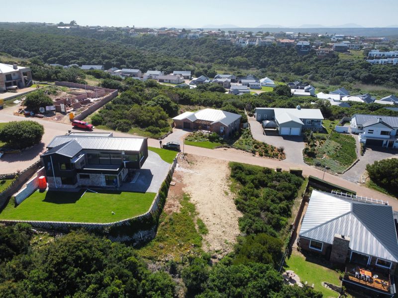 Aerial view of a vacant residential plot situated within an established neighborhood, featuring clear access and surrounding residential infrastructure.