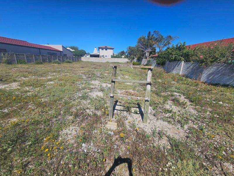 A vacant residential plot featuring a perimeter boundary wall and natural ground cover, offering a blank canvas for future development.