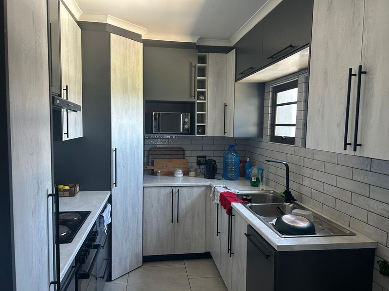 Modern kitchen featuring two-tone cabinetry, subway tile backsplash, double stainless steel sink, and integrated appliances including an oven and hob.