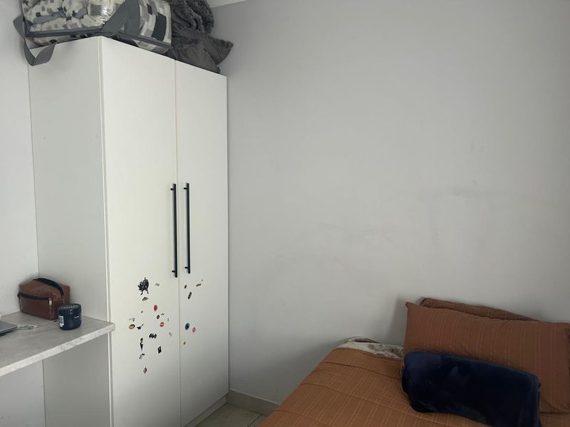 A bedroom featuring a white built-in wardrobe with modern handles and neutral wall finishes.