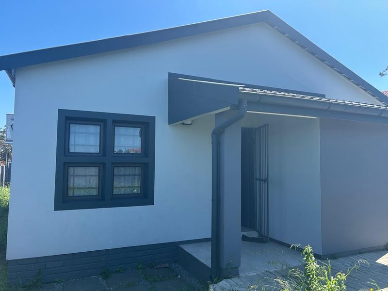Front facade of a modern house featuring a tiled roof, dark grey window frames, and a covered entrance with a security gate.