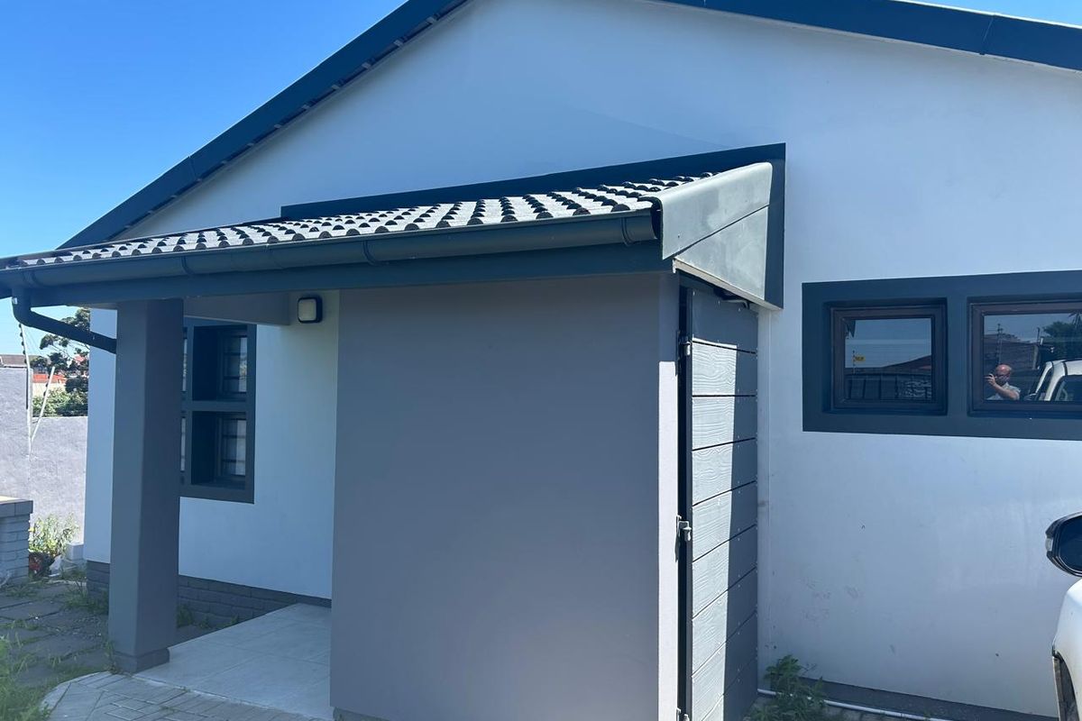 A modern front exterior view of the house featuring a covered entrance, tiled roof, and paved driveway with clean, contemporary finishes.