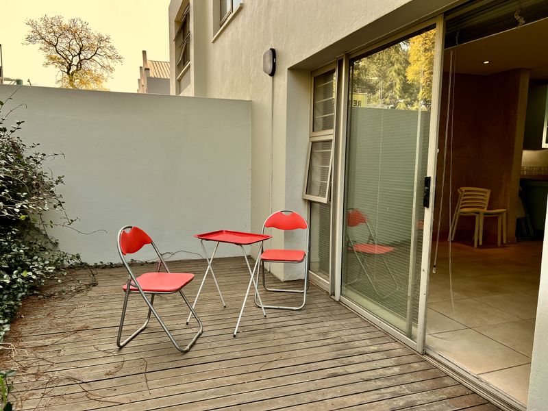 A private outdoor patio area featuring timber decking and direct access to the interior through a large sliding glass door.