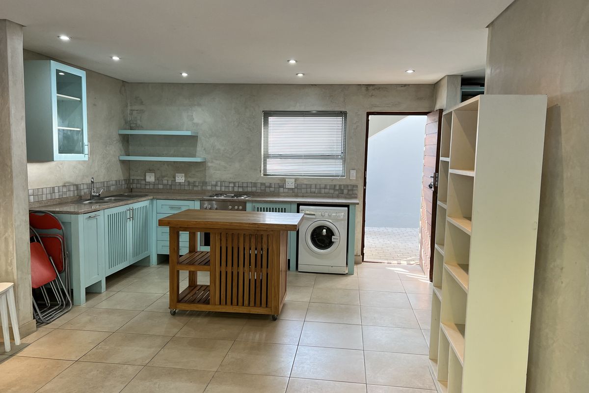 Kitchen featuring light blue cabinetry, tiled flooring, built-in oven and hob, and integrated laundry space with direct access to an outdoor area.
