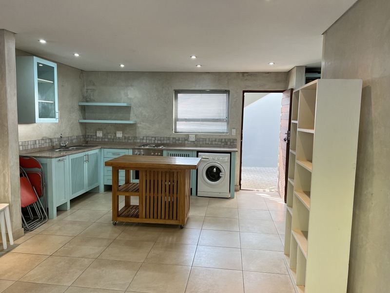 Kitchen featuring light blue cabinetry, tiled flooring, built-in oven and hob, and integrated laundry space with direct access to an outdoor area.