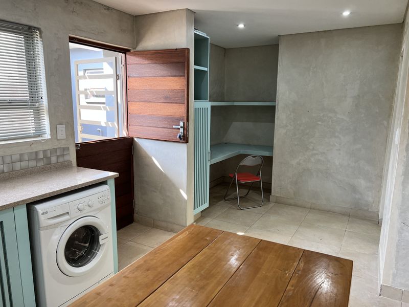 Functional laundry area featuring built-in cabinetry, a dedicated workspace with shelving, tiled flooring, and direct access to the exterior via a stable door.