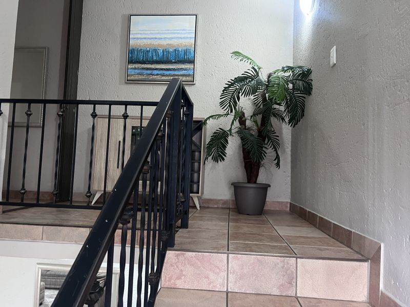 A tiled staircase landing featuring a decorative wrought iron balustrade and textured wall finishes, providing a functional transition space within the townhouse.