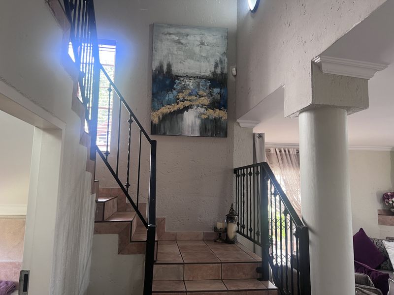 An interior entry area featuring a tiled staircase with a wrought iron balustrade and a prominent structural column.